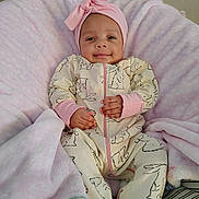 Zoei Zuliana is registered to the contest to win money with this photo: baby, infant, smiling, headband, bow, pink, blanket, onesie, patterned_clothing, zipper, hands, cozy, plush, soft, lying_down, portrait, eyes_open, cheeks, wall, tiny_person