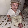 Abraham a rejoint le concours — aidez-le/la à gagner de superbes lots ! baby, child, infant, cap, shirt, pants, bed, bed_sheet, teddy_bear_pattern, smile, sitting, barefoot, bracelet, cute, indoors, furniture, pillow, headwear, clothing, person