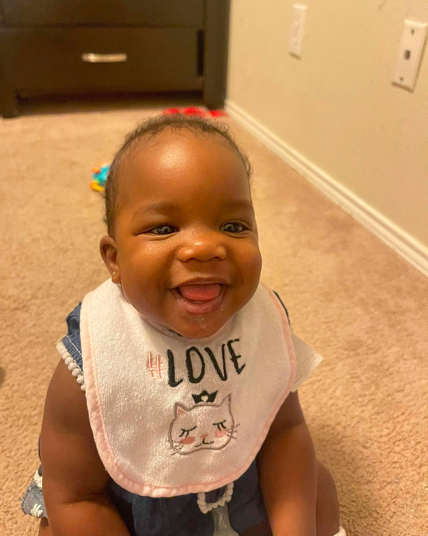 Amari is registered to the contest to win money with this photo: arm, baby, baby_toddler_clothing, cheek, eye, eyebrow, flooring, hair, happy, head, human_body, iris, joy, lip, mouth, neck, nose, person, shoulder, skin
