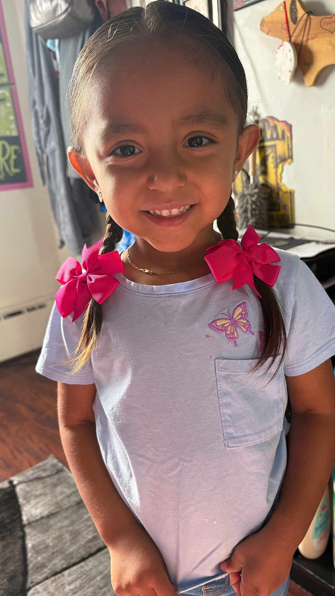 Remie joined the competition — help win amazing prizes! child, girl, smile, braids, pink_bows, white_shirt, butterfly, indoor, portrait, happy, young, cute, earrings, necklace, standing, wood_floor, casual_clothing, home, natural_light, person