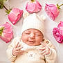 newborn, baby, infant, smile, knit_hat, knit_sweater, bear_ears, pink_roses, flowers, floral_arrangement, white_background, peaceful, cute, cozy, portrait, hands, closed_eyes, soft_light, indoor, adorable