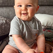 Reece joined the competition — help win amazing prizes! baby, infant, toddler, smiling, sitting, toy, colorful_toy, onesie, gray_shirt, chubby_cheeks, couch, blanket, indoor, portrait, cute, hand, feet, play, face, eyes