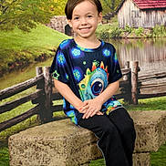 Owen Ernest is registered to the contest to win money with this photo: child, smiling, sitting, stone_bench, colorful_shirt, outdoor, fence, pond, barn, grass, tree, nature, portrait, casual_clothing, happy, young_person, scenic, daylight, greenery, relaxed