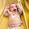 baby, infant, smiling, happy, face, clothing, sweater, bear_design, blanket, yellow, cute, child, young, lying_down, expression, indoor, soft_texture, warm_colors, hoodie, small_hands