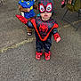 Koa is registered to the contest to win money with this photo: child, toddler, costume, spiderman, police_officer, mask, outdoor, pavement, footwear, backpack, person, toy, hat, clothing, dress_up, cute, playing, people, standing, fun
