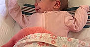 Athena is registered to the contest to win money with this photo: newborn, baby, infant, child, pink_sleeper, blanket, floral_blanket, crib, bedding, pillow, sleeping, lying_down, face, hands, arms, indoor, nursery, portrait, text, cozy