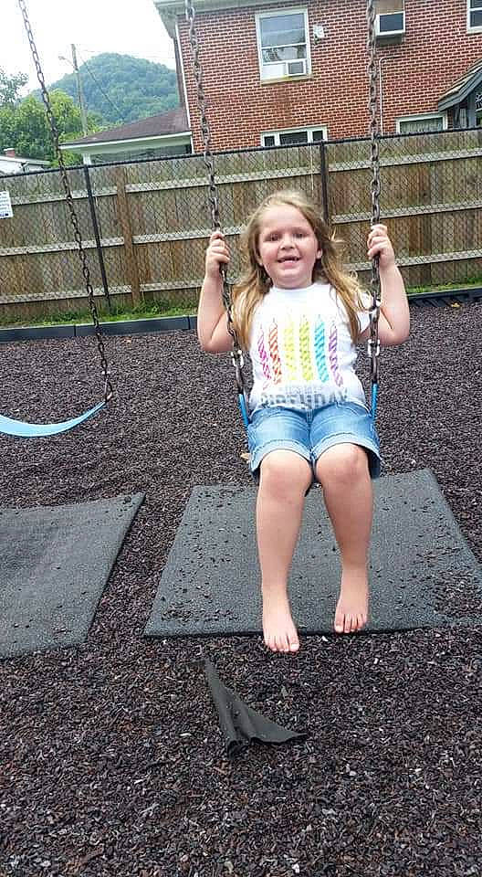 Jojo is registered to the contest to win money with this photo: barefoot, blond, child, denim, fun, grass, joy, leg, outdoor_play_equipment, person, play, playground, public_space, recreation, shorts, smile, snapshot, summer, swing, toddler