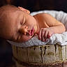 élie a rejoint le concours — aidez-le/la à gagner de superbes lots ! newborn, baby, sleeping, infant, wooden_bucket, blanket, soft_texture, peaceful, portrait, close_up, skin, hand, face, indoors, warm_lighting, rest, cute, tender, newborn_photography, cozy