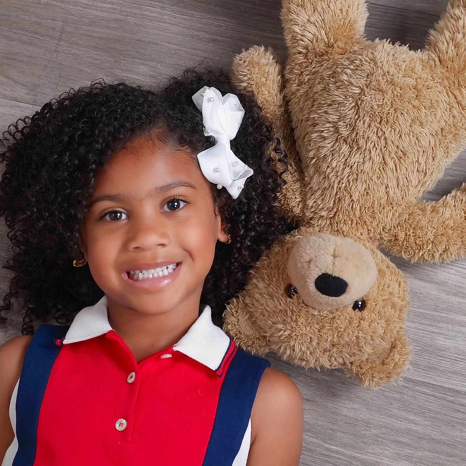 Ariana is registered to the contest to win money with this photo: blackhair, bodypart, child, clothing, curlyhair, face, female, girl, hair, happy, head, mouth, person, photography, portrait, sleeve, smile, student, teeth, toy