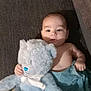 baby, teddy_bear, plush_toy, blanket, sofa, couch, infant, child, indoor, cute, soft_toy, blue, person, face, hand, lying_down, cozy, smiling, young, comfort