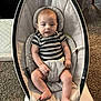 Tommy is registered to the contest to win money with this photo: baby, infant, striped_onesie, baby_rocker, carpet, indoor, child, person, furniture, seat, legs, arms, head, face, comfort, relaxing, home, newborn, cute, toddler
