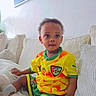 David Afanbo participe au concours pour gagner de l'argent avec cette photo : toddler, child, soccer_jersey, yellow_clothing, green_clothing, socks, indoor, couch, pillows, blanket, portrait, curious, seated, home_interior, wall_art, soft_light, cozy, person, baby, casual