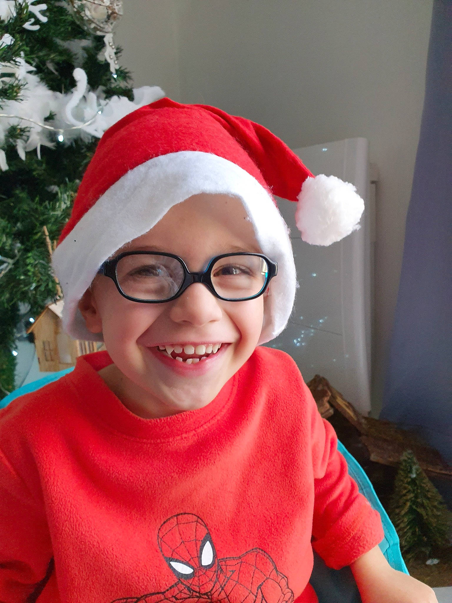 Ethan participe au concours pour gagner de l'argent avec cette photo : child, christmas, christmas_eve, christmas_ornament, ear, fictional_character, glasses, happy, holiday, joy, person, red, santa_claus, smile