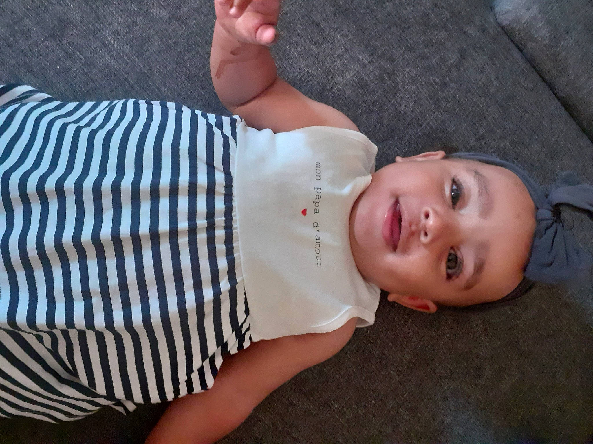 Maïssa participe au concours pour gagner de l'argent avec cette photo : abdomen, baby, baby_toddler_clothing, chest, dress_shirt, elbow, finger, hat, headgear, human_leg, neck, pattern, person, sleeve, smile, thigh, toddler, trunk, waist, wood