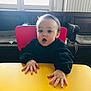 toddler, child, baby, surprised_expression, yellow_table, pink_chair, hands, face, indoor, window, bench, wooden_bench, radiator, sweater, portrait, mouth_open, tabletop, highchair, seated, natural_light
