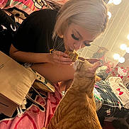 Pumpkin is registered to the contest to win money with this photo: person, cat, indoor, bed, blanket, food, orange_tabby, pet, feeding, curious, blonde_hair, mirror, lights, jewelry, bag, casual, clothing, comfort, playful, animal