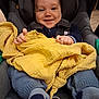 baby, blanket, blue_clothing, car_seat, child, clothing, comfort, cozy, cute, face, hands, happy, indoor, infant, portrait, seatbelt, smiling, socks, toddler, yellow_blanket