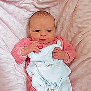 Ambre participe au concours pour gagner de l'argent avec cette photo : baby, newborn, infant, pink_blanket, pink_clothing, onesie, soft_texture, cute, cozy, sleepy_animal, embroidered_text, portrait, indoor, closeup, child, face, hand, lying_down, person, warm