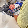 Oakland is registered to the contest to win money with this photo: newborn, baby, hospital, sink, water, gloves, person, hand, blanket, bath, infant, towel, medical, cleaning, face, expression, clothing, counter, bottle, healthcare