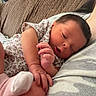 baby, infant, newborn, sleeping, couch, floral_clothing, hand, foot, sock, resting, cozy, indoor, person, skin, face, parent, comfort, soft_lighting, home, relaxation