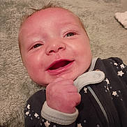 Everette is registered to the contest to win money with this photo: baby, smiling, infant, onesie, stars, blanket, soft_texture, cute, happy, face, hand, portrait, child, lying_down, indoors, cozy, expression, skin, clothing, person