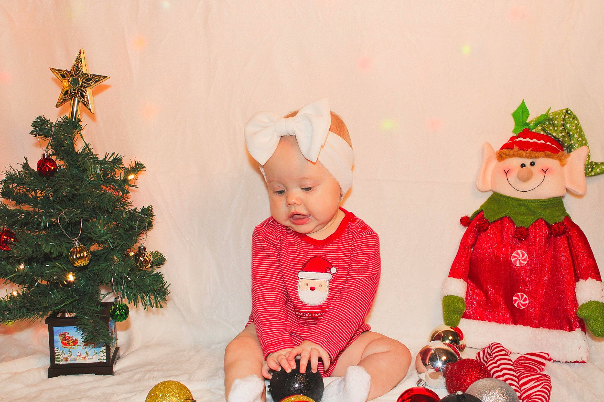 Aubree is registered to the contest to win money with this photo: baby, baby_toddler_clothing, christmas_decoration, christmas_eve, christmas_ornament, christmas_tree, costume_hat, event, evergreen, happy, hat, headwear, holiday, holiday_ornament, lighting, ornament, person, red, santa_claus, toddler