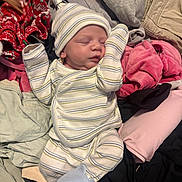 Lukas is registered to the contest to win money with this photo: newborn, baby, sleeping, infant, portrait, striped_clothing, hat, mittens, onesie, blanket, laundry, clothing, pink, red, gray, indoors, lying_down, peaceful, cute, photography