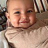 baby, smile, blanket, wooden_chair, indoors, face, child, cozy, cute, portrait, warm_clothing, furniture, happy, infant, person, wrapped, home, soft, seated, closeup