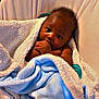 Ahdyssea is registered to the contest to win money with this photo: baby, blanket, blue_blanket, cushion, infant, pacifier, seat, child, hand, face, curious, cozy, indoor, wrapped, soft_texture, skin, portrait, comfort, young_child, resting
