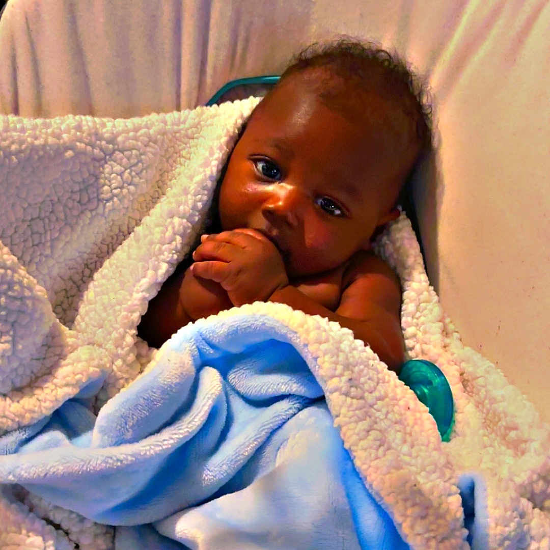 Ahdyssea is registered to the contest to win money with this photo: baby, blanket, blue_blanket, child, comfort, cozy, curious, cushion, face, hand, indoor, infant, pacifier, portrait, resting, seat, skin, soft_texture, wrapped, young_child