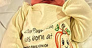 Orion joined the competition — help win amazing prizes! newborn, baby, infant, sleeping, portrait, hospital, hospital_bed, onesie, baby_clothing, knit_cap, striped_hat, blanket, swaddled, face, closed_eyes, peaceful, cartoon, pumpkin, text_on_clothing, indoor