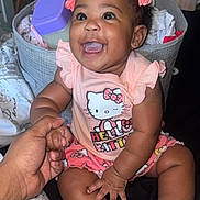 Pryceless is registered to the contest to win money with this photo: baby, child, smiling, happy, hand, holding, hello_kitty, clothing, pink, hair_bow, socks, indoor, furniture, basket, blanket, person, cute, infant, sitting, portrait