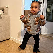 Cataleya participe au concours pour gagner de l'argent avec cette photo : toddler, child, indoor, sweater, teddy_bear, smiling, curly_hair, wooden_floor, pants, shoes, doorway, furniture, couch, wall, home, person, happy, walking, cute, portrait