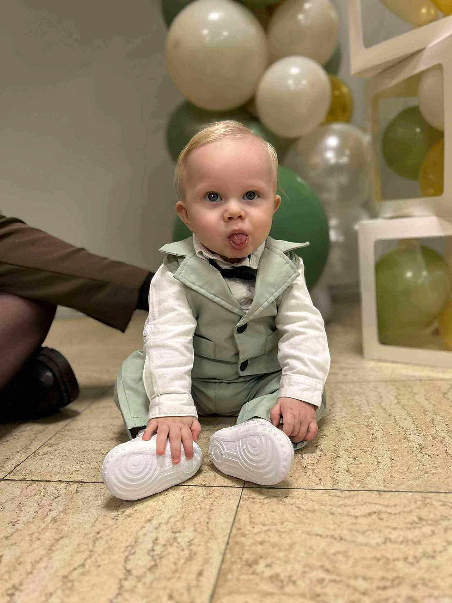Maylon a rejoint le concours — aidez-le/la à gagner de superbes lots ! baby, child, toddler, sitting, formal_clothing, bow_tie, balloons, party, indoor, portrait, white_shoes, hands, tongue_out, blond_hair, blue_eyes, tile_floor, cute, adorable, celebration, event