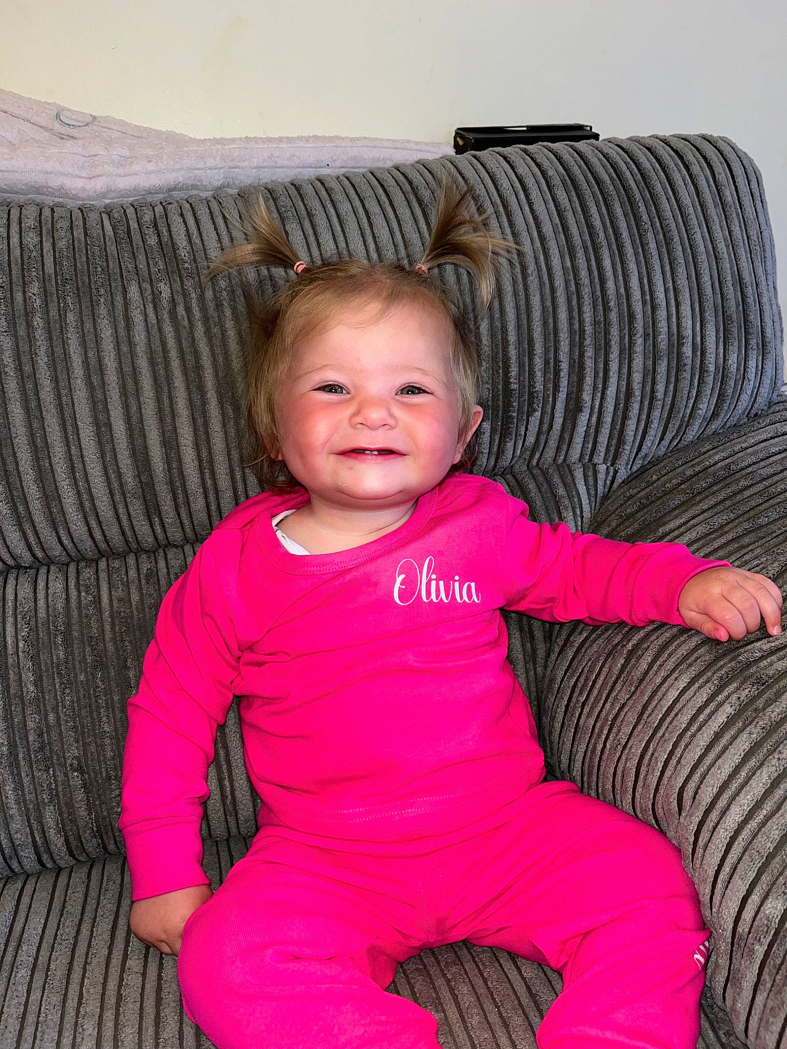 Olivia is registered to the contest to win money with this photo: baby, baby_toddler_clothing, cheek, comfort, couch, eye, fun, furniture, hair, happy, head, iris, joy, lap, magenta, person, pink, purple, sitting, sleeve