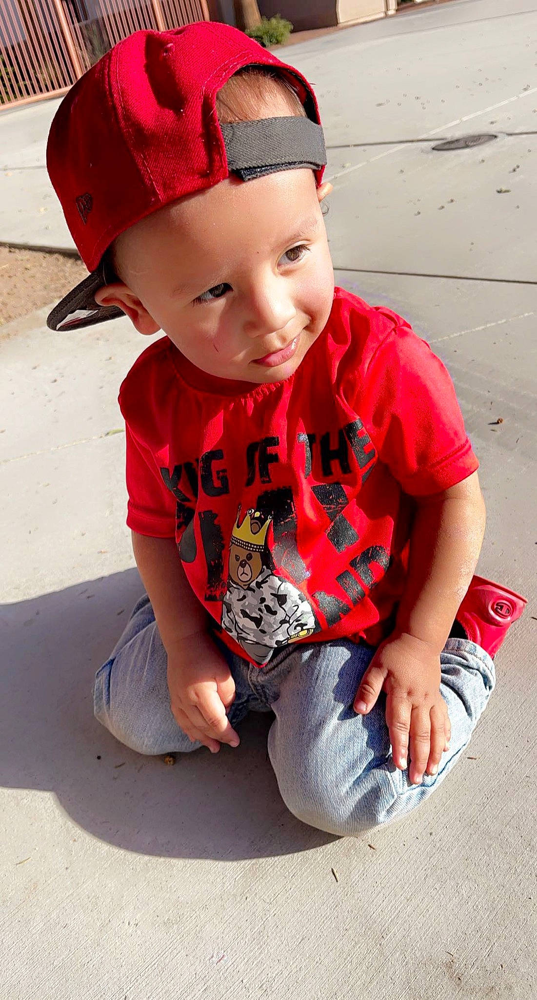 Leonel is registered to the contest to win money with this photo: cap, child, chin, cool, costume_hat, facial_expression, fun, grass, hairstyle, happy, headgear, jeans, knee, lip, person, red, sitting, sleeve, t_shirt, thigh