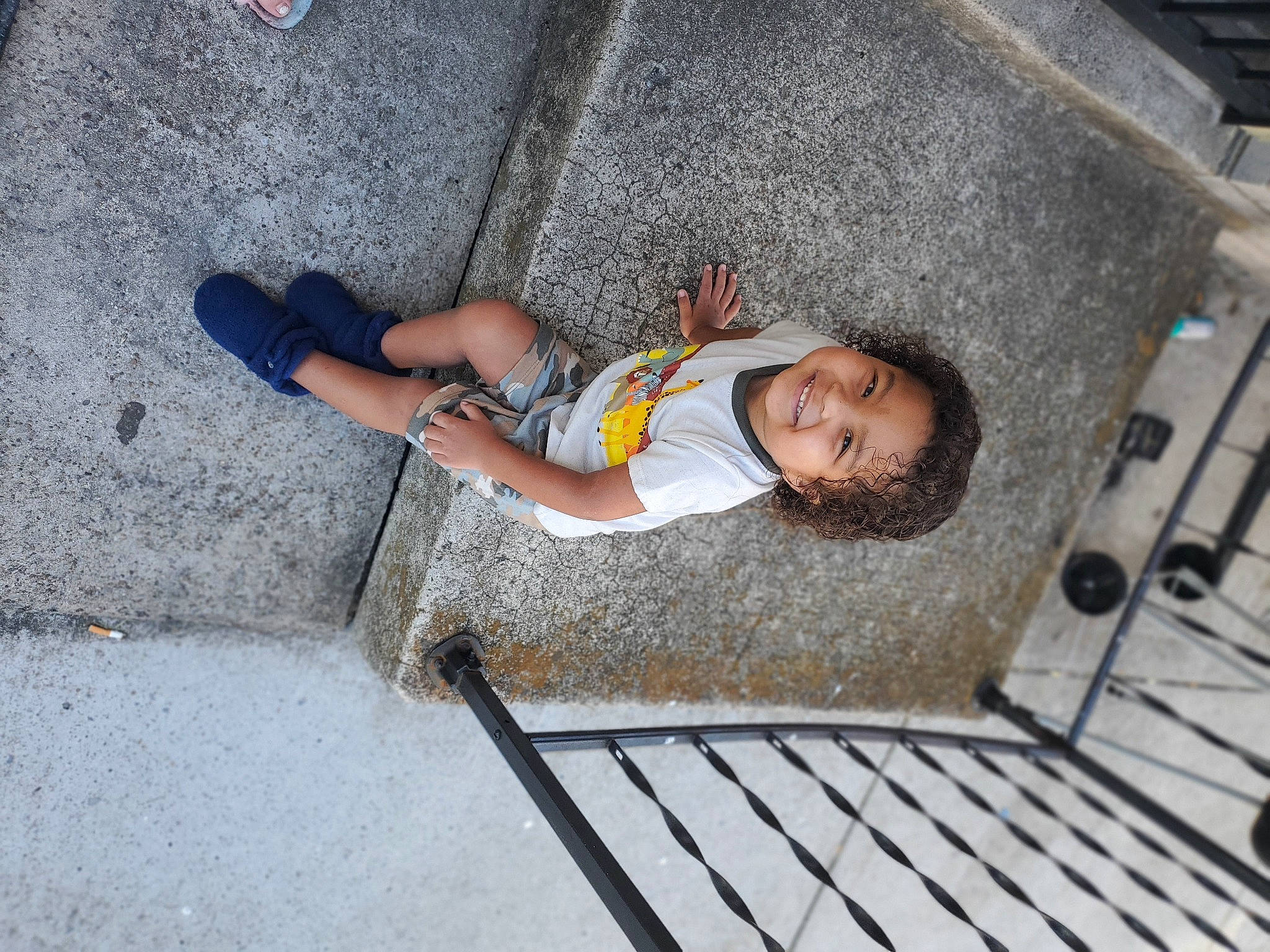 Dwaine is registered to the contest to win money with this photo: asphalt, child, comfort, concrete, flooring, foot, fun, grass, grey, human_leg, joint, joy, knee, leisure, person, road_surface, sidewalk, sunglasses, thigh, toddler