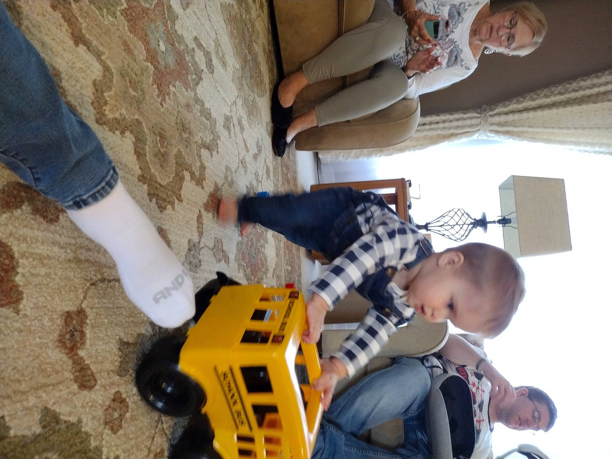 Troy is registered to the contest to win money with this photo: automotive_exterior, child, flooring, fun, human_leg, leg, leisure, machine, motor_vehicle, pattern, person, personal_protective_equipment, play, recreation, room, shoe, sneakers, soil, toddler, toy