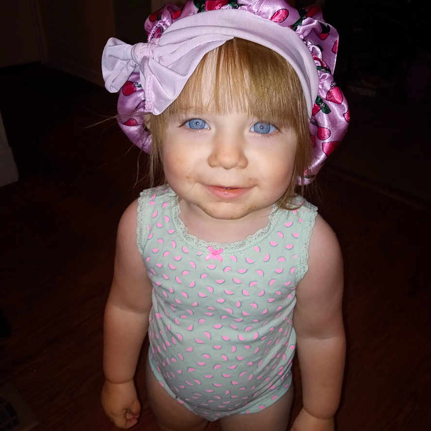Charlee is registered to the contest to win money with this photo: toddler, child, indoor, blue_eyes, bonnet, onesie, smile, person, standing, floor, hair, curious, young_child, apparel, headwear, skin, portrait, baby, cute, childhood