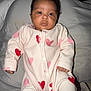 Ashanti participe au concours pour gagner de l'argent avec cette photo : baby, infant, onesie, heart_pattern, clothing, face, portrait, sleepwear, cute, child, young, lying_down, soft_surface, indoor, warm, comfort, small_hands, curly_hair, expression, looking