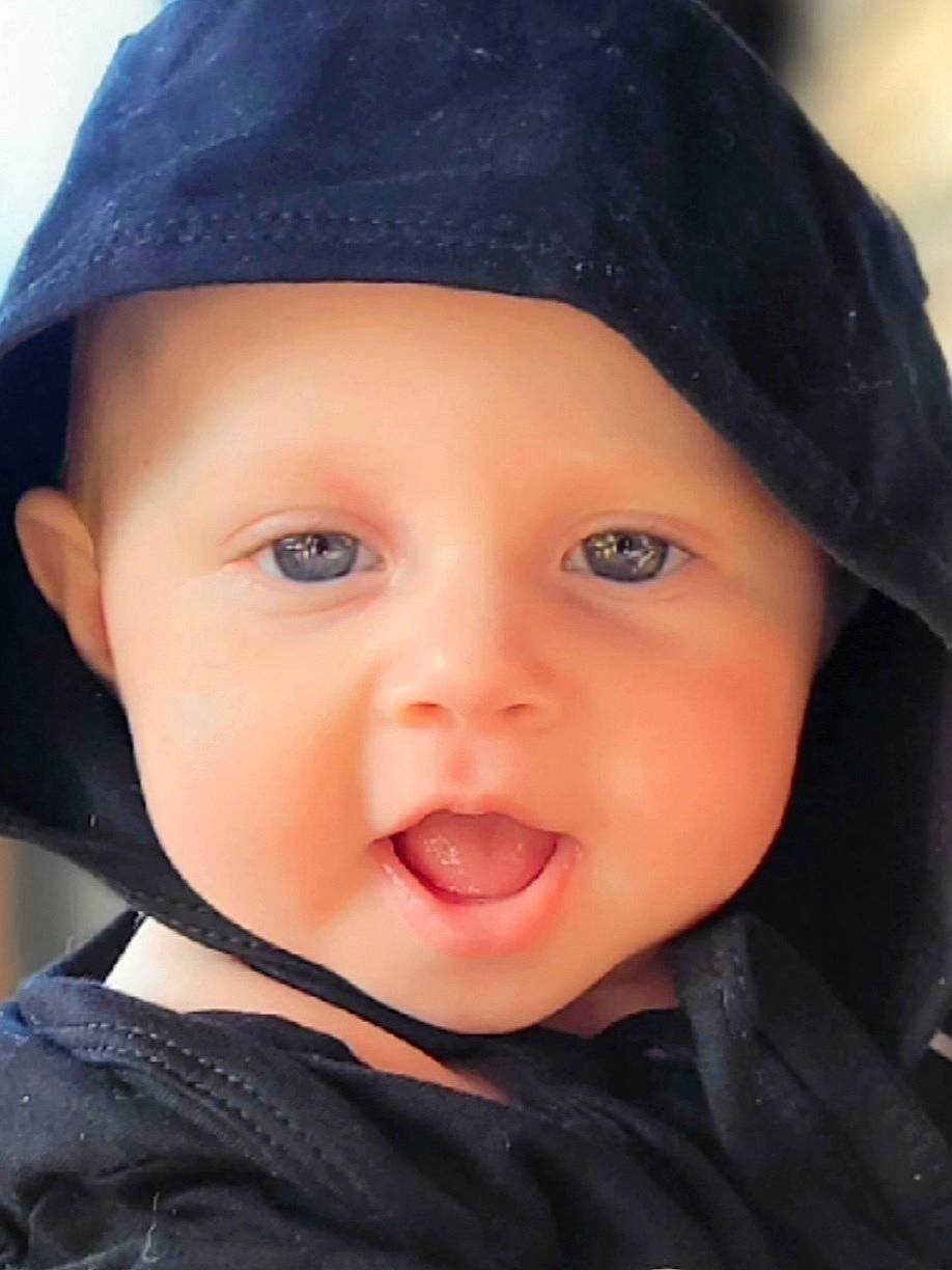 Veronica is registered to the contest to win money with this photo: baby, black_hair, cap, cheek, chin, close_up, cool, eye, eyebrow, face, flash_photography, happy, hat, headgear, headwear, lip, nose, outerwear, person, sleeve