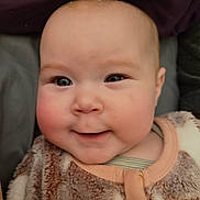 Nina participe au concours pour gagner de l'argent avec cette photo : baby, infant, face, rosy_cheeks, smile, blue_eyes, onesie, pajamas, fuzzy_texture, closeup, portrait, indoor, head, skin, mouth, cheeks, cozy, blanket, adorable, eyes