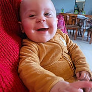 Tom a rejoint le concours — aidez-le/la à gagner de superbes lots ! baby, smiling, child, indoor, red_blanket, yellow_clothing, hand, face, happy, portrait, cozy, dining_room, furniture, wooden_chairs, table, home, person, infant, cute, warm_lighting