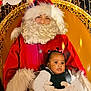 Anayah a rejoint le concours — aidez-le/la à gagner de superbes lots ! baby, child, santa_claus, christmas, holiday, festive, red_clothing, beard, glasses, chair, lights, portrait, indoor, cute, smiling, people, celebration, winter, costume, hair_ties