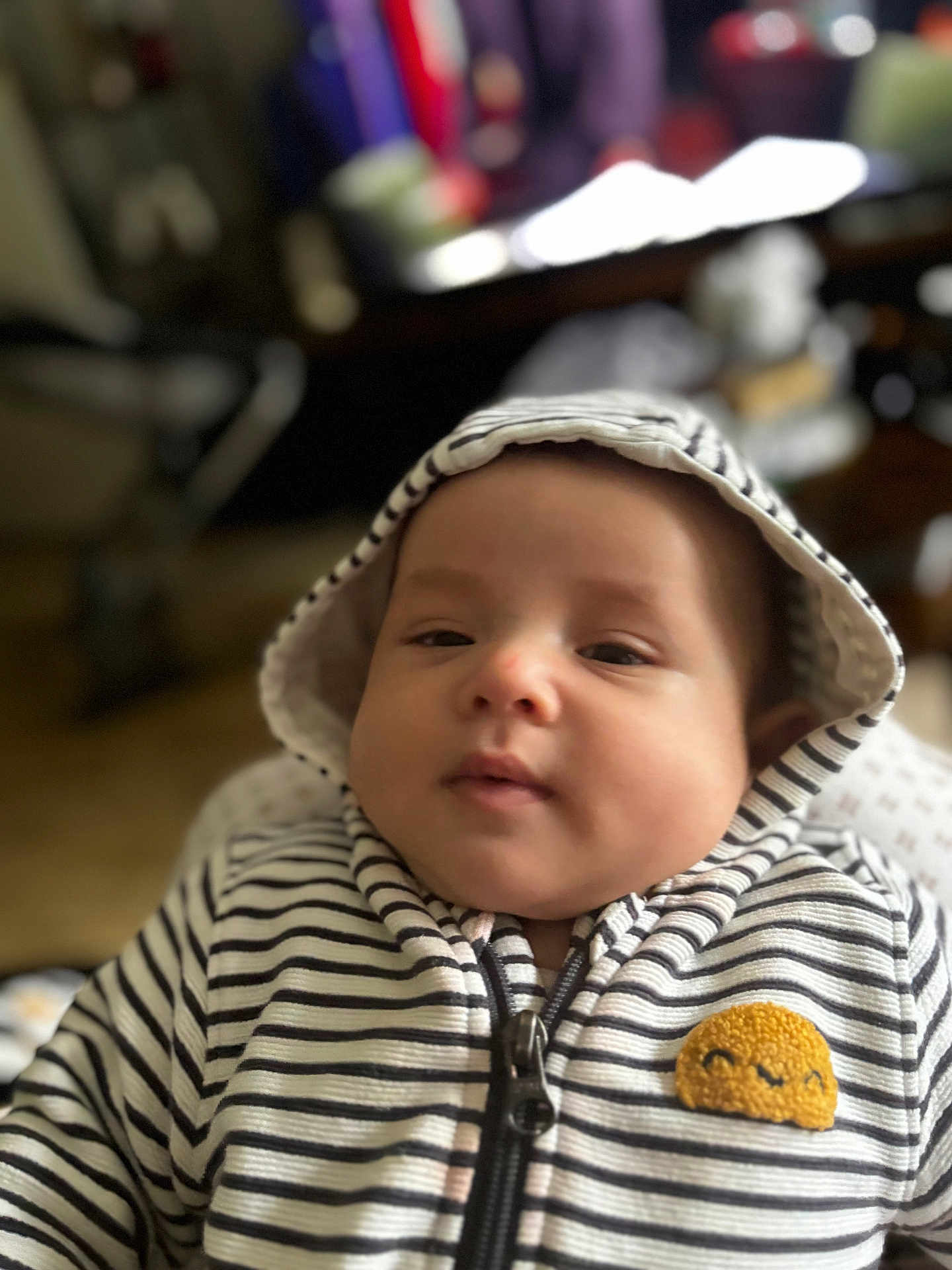 Tianay a rejoint le concours — aidez-le/la à gagner de superbes lots ! baby, child, hoodie, striped_clothing, face, cute, indoor, portrait, smiling_patch, young_child, apparel, zipper, infant, person, casual_wear, headwear, expression, soft_focus, warm_lighting, young