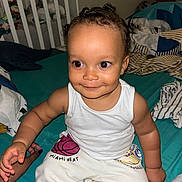 Christian a rejoint le concours — aidez-le/la à gagner de superbes lots ! basketball, bed, bedroom, blanket, casual_clothing, child, crib, cute, face, hand, happy, indoors, miami_heat, person, sitting, skin, smiling, sweatpants, toddler, white_tank_top