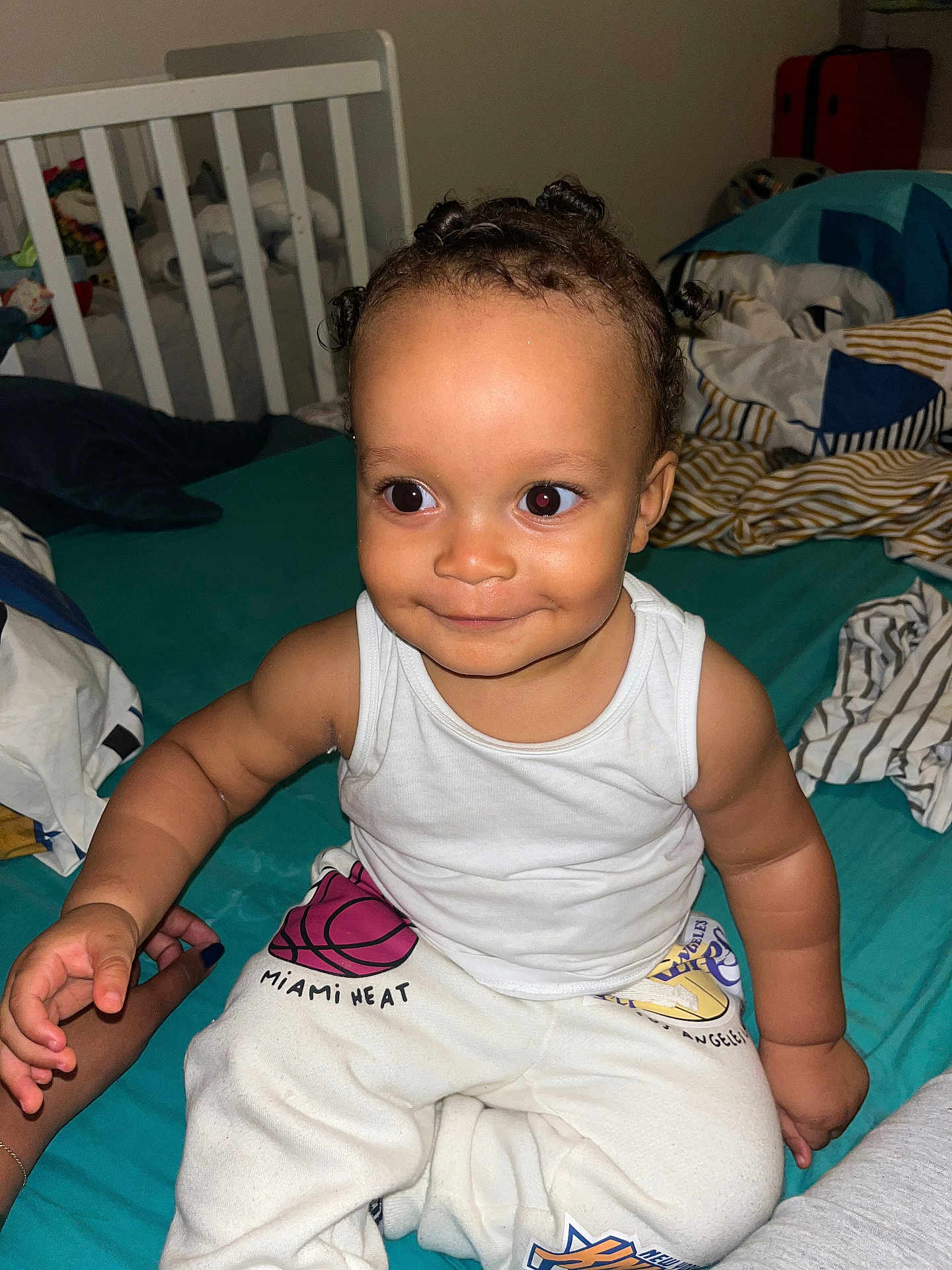 Christian a rejoint le concours — aidez-le/la à gagner de superbes lots ! basketball, bed, bedroom, blanket, casual_clothing, child, crib, cute, face, hand, happy, indoors, miami_heat, person, sitting, skin, smiling, sweatpants, toddler, white_tank_top