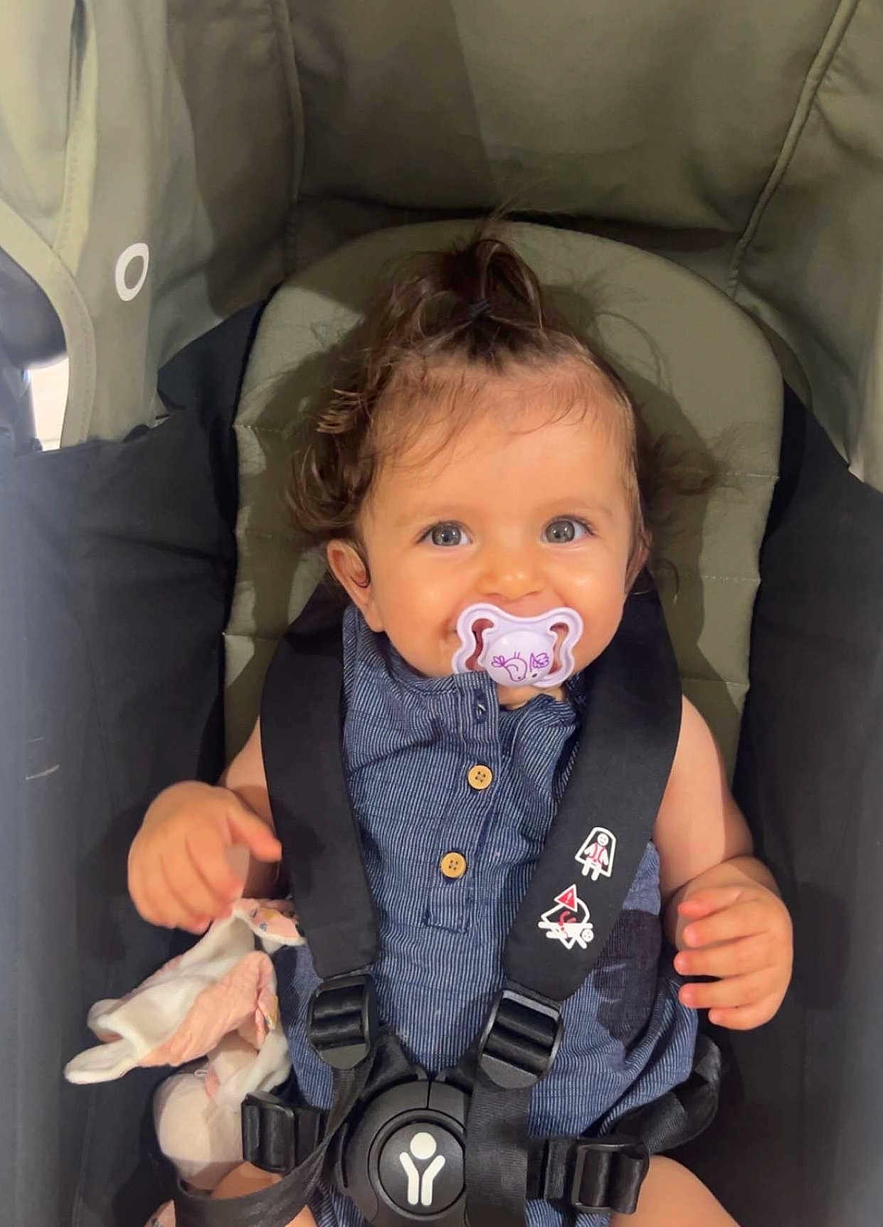 Leya a rejoint le concours — aidez-le/la à gagner de superbes lots ! baby, pacifier, stroller, child, blue_outfit, soft_toy, smiling, happy, curly_hair, seatbelt, infant, cute, indoor, person, portrait, safety_harness, young_child, holding, seated, face
