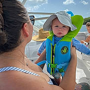 Edward Eible is registered to the contest to win money with this photo: baby, child, woman, boat, life_jacket, hat, tattoo, water, river, trees, sunlight, sunglasses, person, outdoor, summer, family, portrait, clothing, nature, recreation