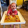 baby, child, feeding, food, footwearless, furniture, happy, high_chair, home, indoor, kitchen, messy, person, plate, red_clothing, scrambled_eggs, smiling, strawberries, table, wood_floor